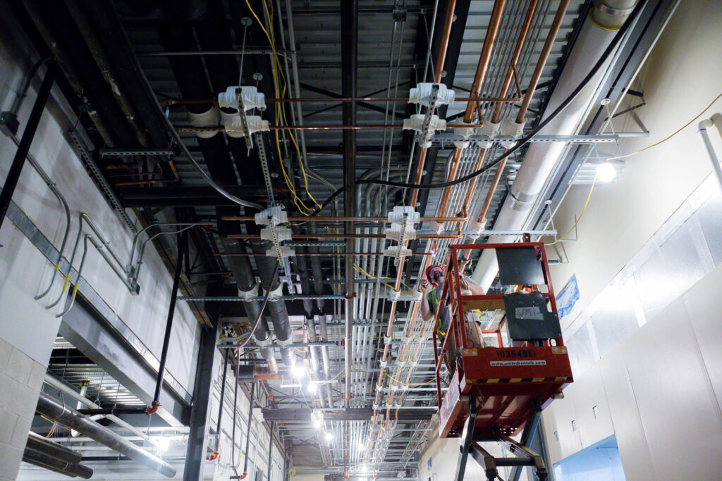 employee working on custom water piping on the ceiling of a commercial building