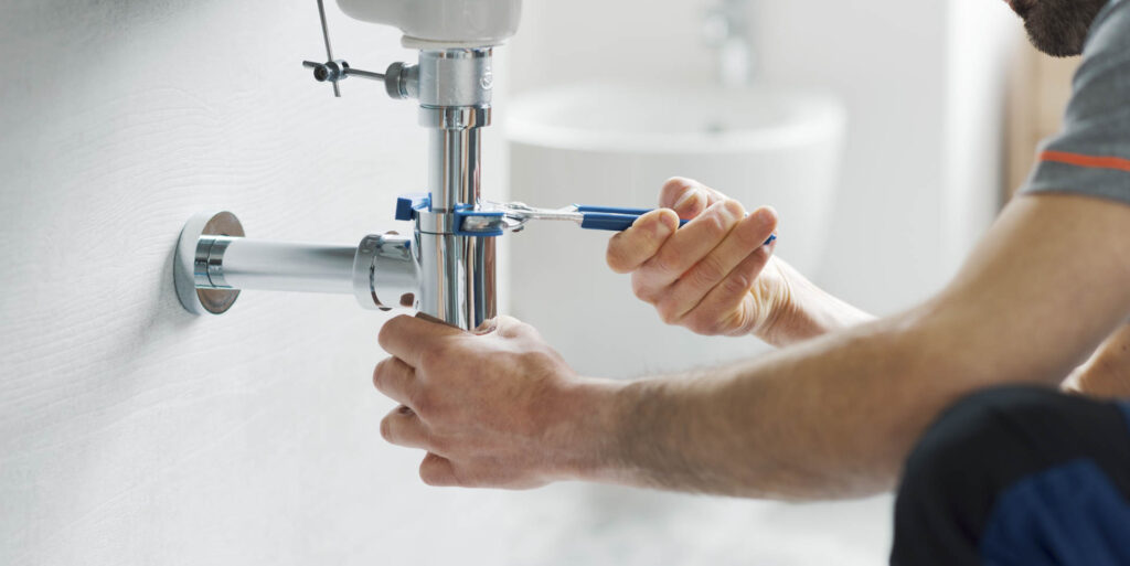 Professional plumber fixing a bathroom sink drain using water pump pliers